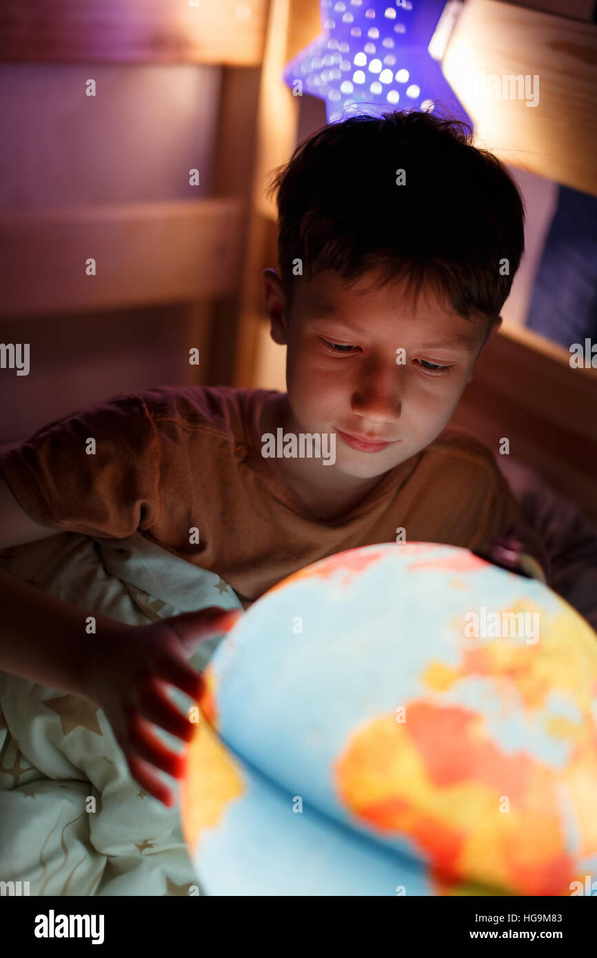 Kleiner Junge Länder auf der ganzen Welt zu entdecken, in der Nacht im Bett studieren Stockfoto