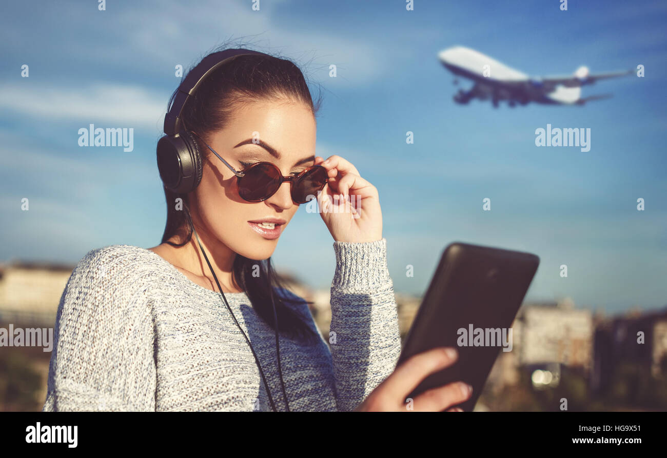 Junge Frau, die Bestellung von Flugtickets per Tablet am Flughafen Stockfoto