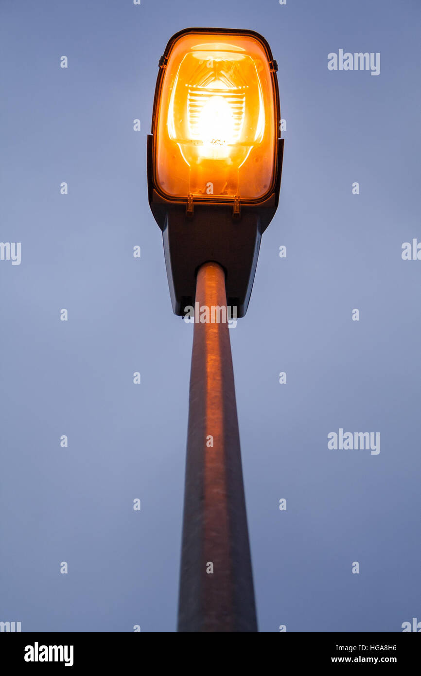 Lit moderne Laterne am Abend oder am frühen Abend mit einem orangefarbenen Lampe und Himmel mit Wolken Stockfoto