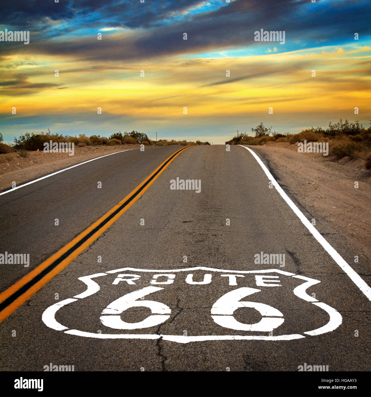 Eine Straße mit einer Route 66 singen auf dem Boden in der Mojave-Wüste in Kalifornien mit einem dynamischen Himmel. Stockfoto