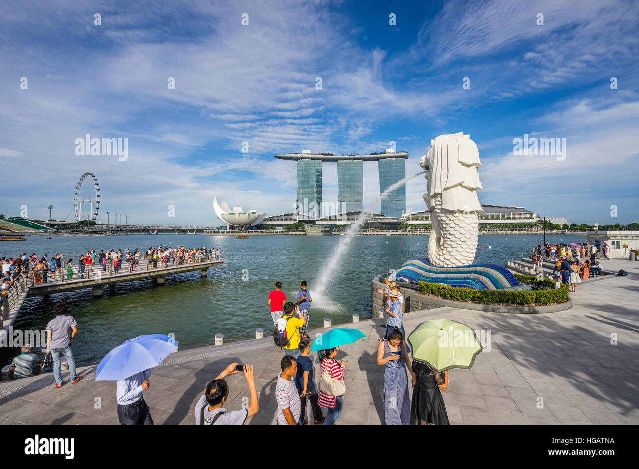 Singapur, Marina Bay, Touristen bewundern die Wasser speienden Merlion Statue vor dem Hintergrund des Marina Bay Sands Resort Und dem Singapore Flyer Stockfoto