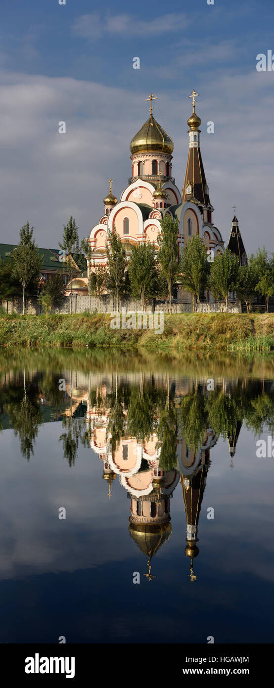 Vertikales Panorama der Kirche der Erhöhung des Heiligen Kreuzes in Almaty-Kasachstan widerspiegelt im noch See Stockfoto