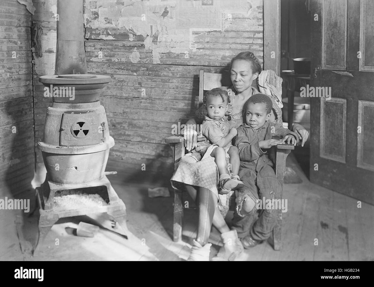 Mutter und ihre zwei Kinder sitzen mit Holzofen, 1937. Stockfoto