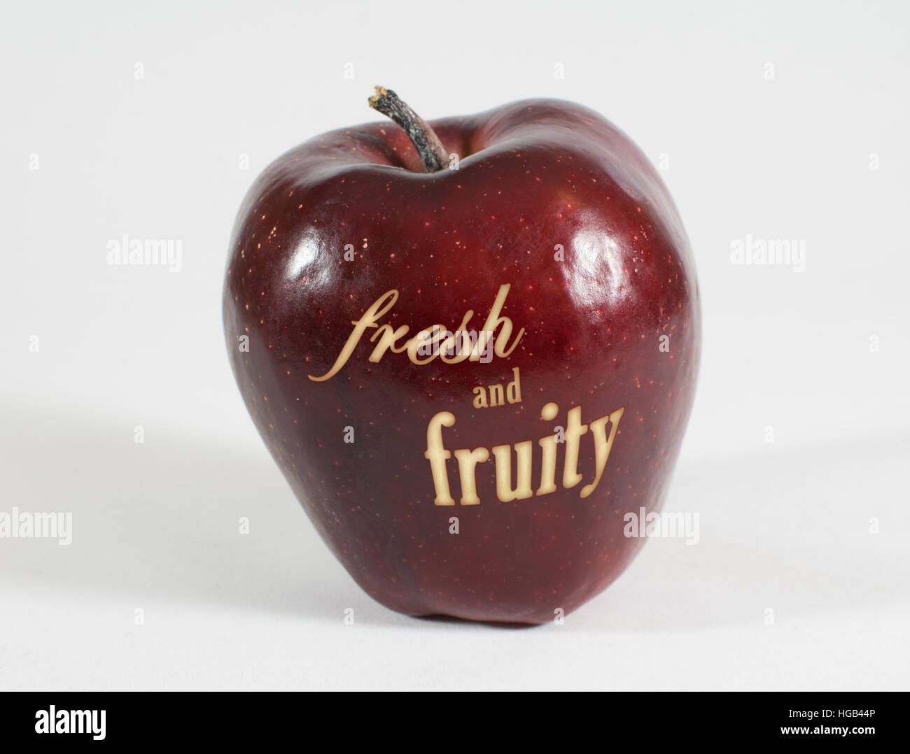1 frische rote Apfel mit der Aufschrift "frisch und fruchtig" auf weißem Hintergrund Stockfoto