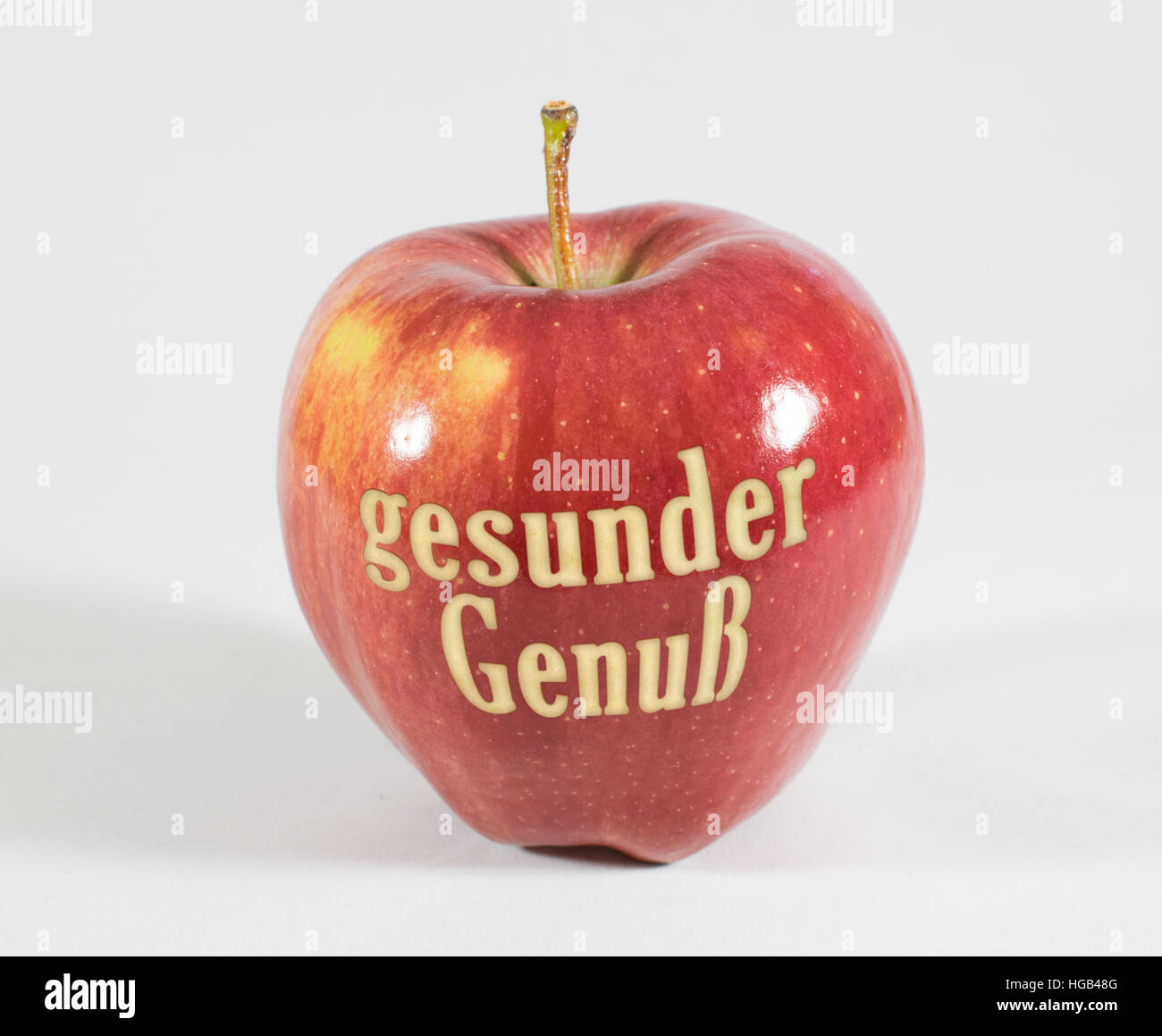 1 frische rote Apfel mit den Worten - gesunden Genuss - in deutscher Sprache auf einem weißen Hintergrund Stockfoto