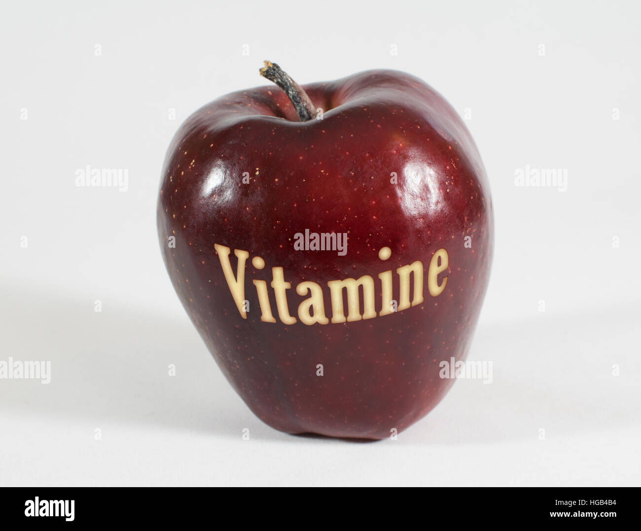 1 frische rote Apfel mit der Aufschrift - Vitamine - im deutschen Wörter auf einem weißen Hintergrund Stockfoto