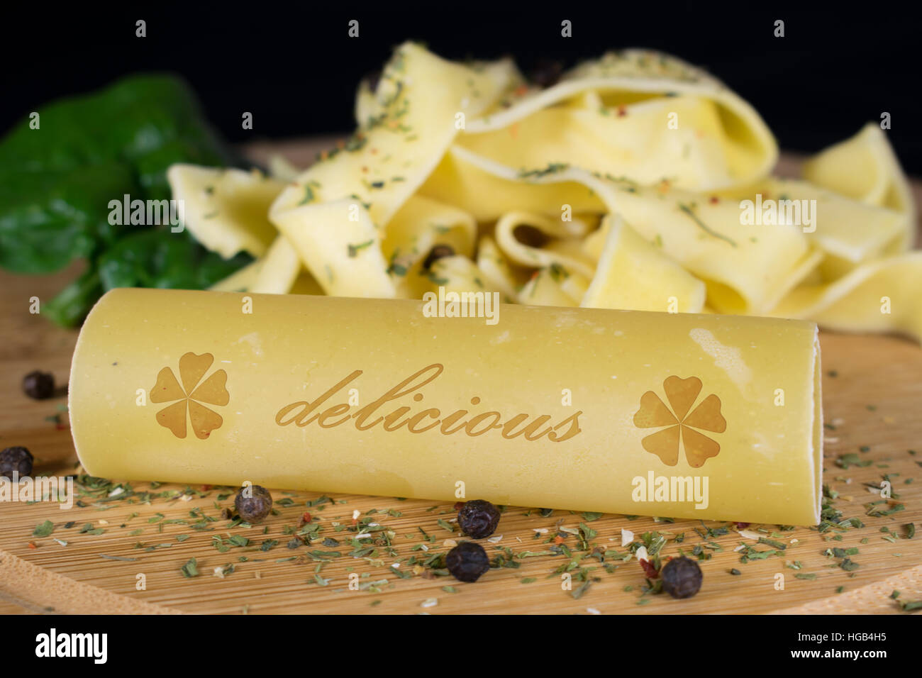 Auf einem Holzbrett steht im Vordergrund ein Cannelloni mit dem Schriftzug - sehr lecker - im Hintergrund sind weitere Nudeln garniert mit Blatt spinac Stockfoto