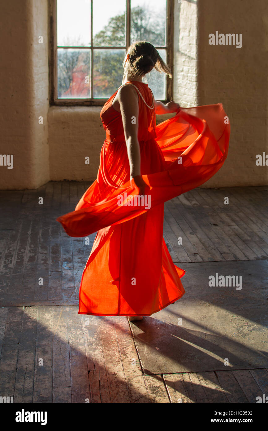 Voller Länge einer Frau im Sommer Kleid tanzen im Innenbereich Stockfoto