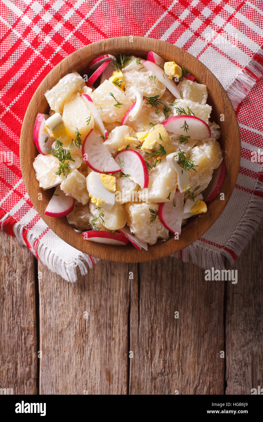 Kartoffelsalat mit Radieschen und Ei in einer Schüssel auf dem Tisch. Vertikale Ansicht von oben Stockfoto