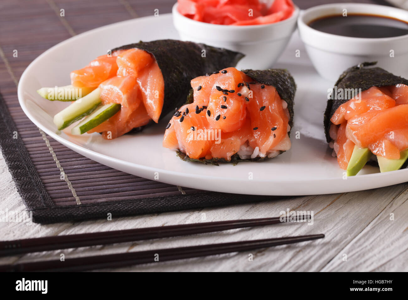 Temaki Lachs Sushi mit Sojasauce und eingelegter Ingwer auf einem weißen Teller hautnah. horizontale Stockfoto