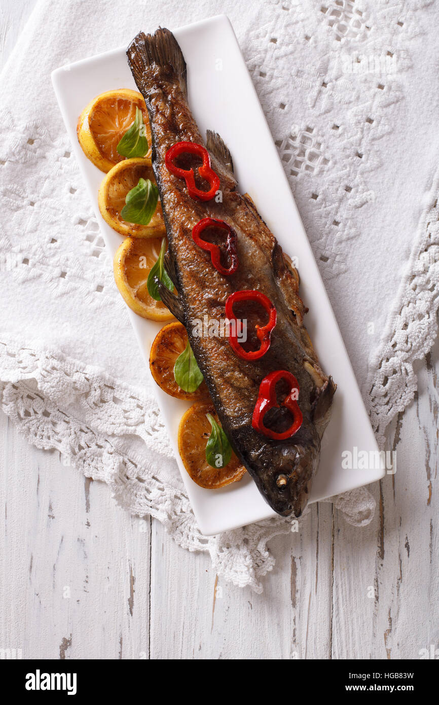 gegrillte Forelle mit Gemüse auf einem Teller auf den Tisch. vertikale Ansicht von oben Stockfoto