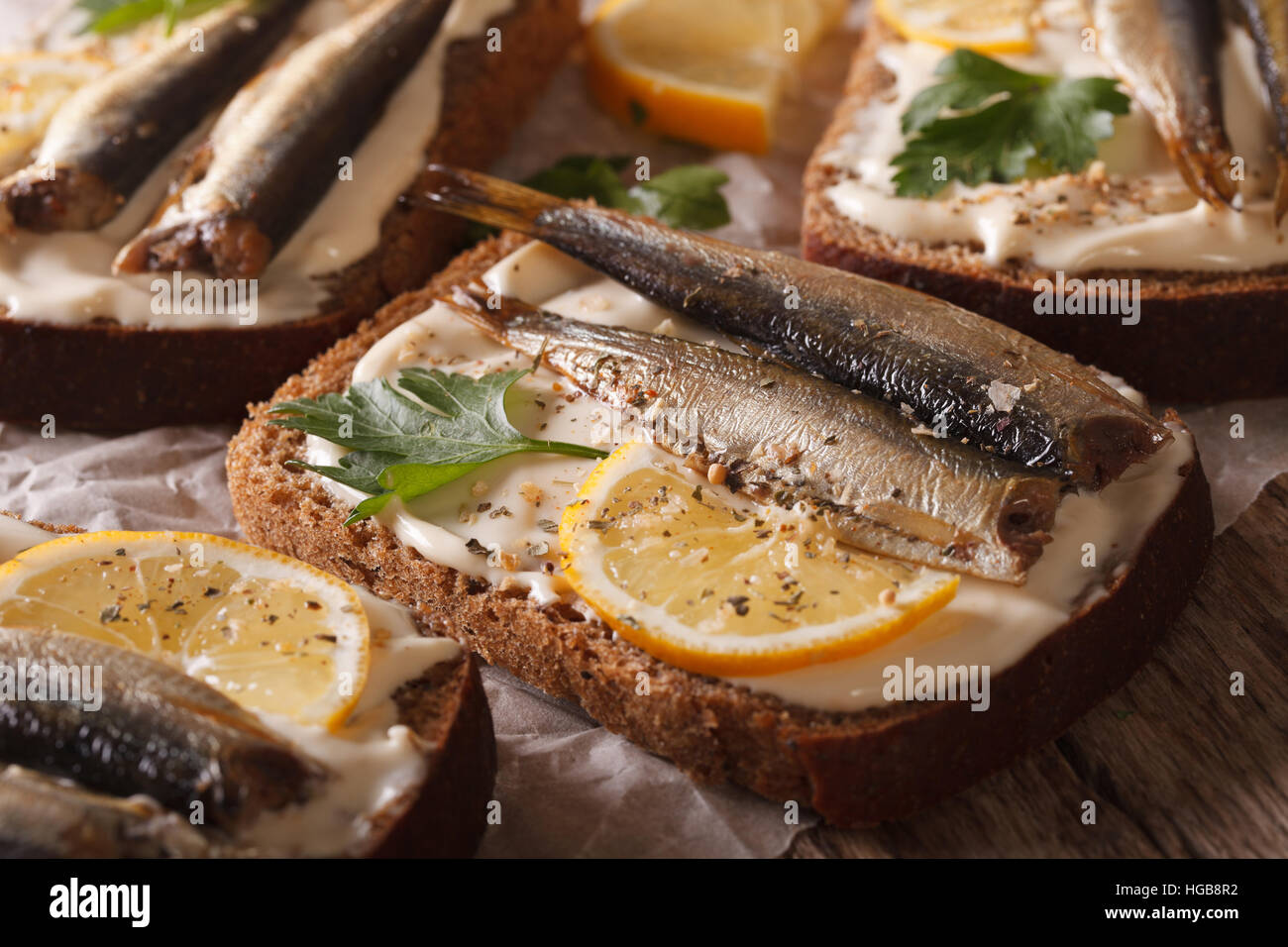 Leckere Fischbrötchen mit Sprotten, Frischkäse und Zitronensaft Makro auf dem Tisch. horizontale Stockfoto