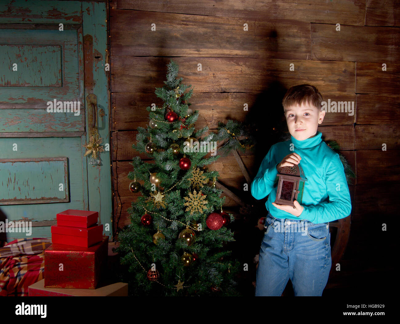 Happy little Boy dekorieren Weihnachtsbaum im schönen Wohnzimmer mit traditionellen Kamin. Stockfoto