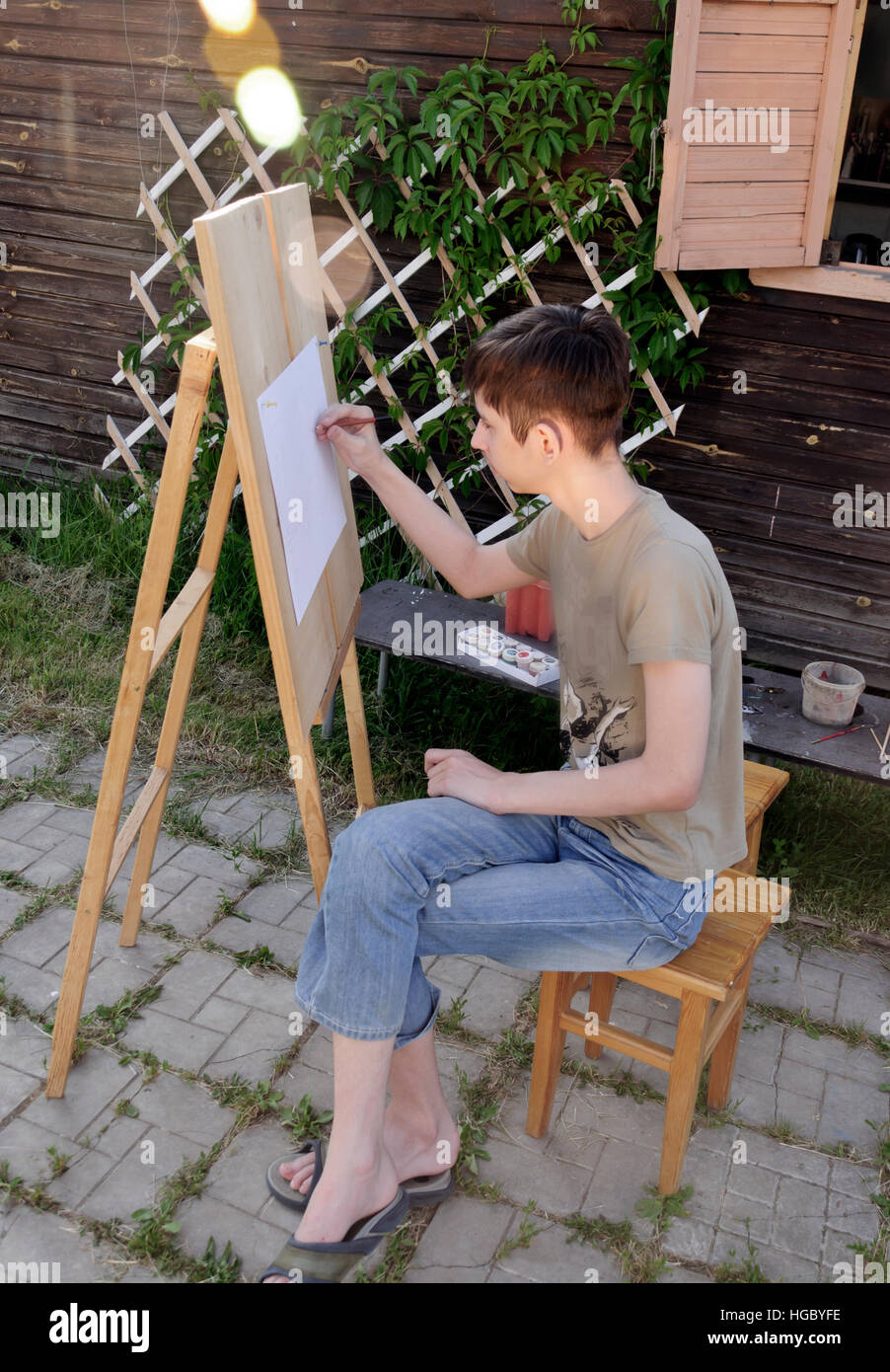 Junge malt an der Staffelei im Garten Stockfoto