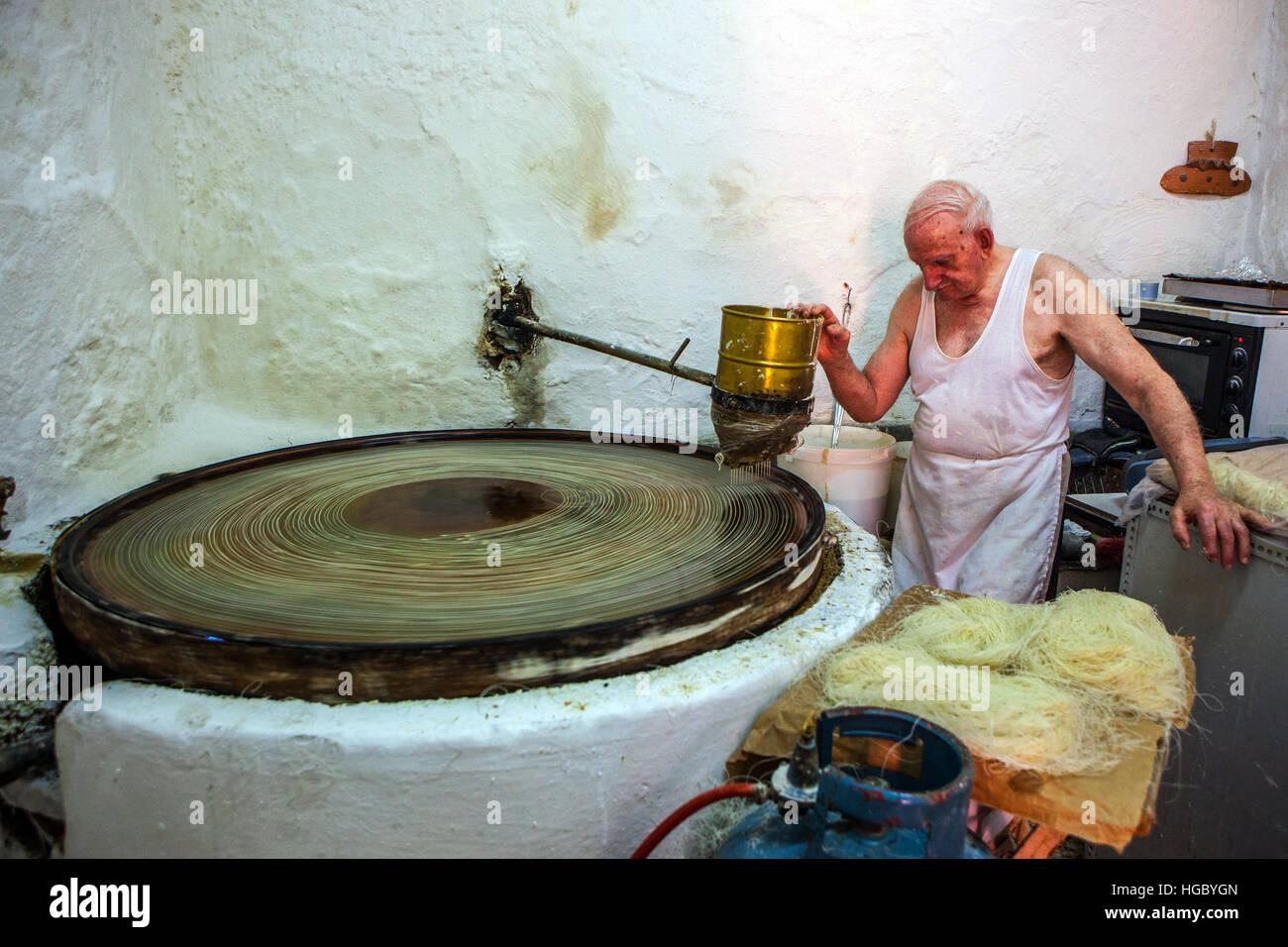 Der ältere Mann, der traditionelle Süßigkeiten in einem Geschäft in Rethymno, kreta macht Stockfoto