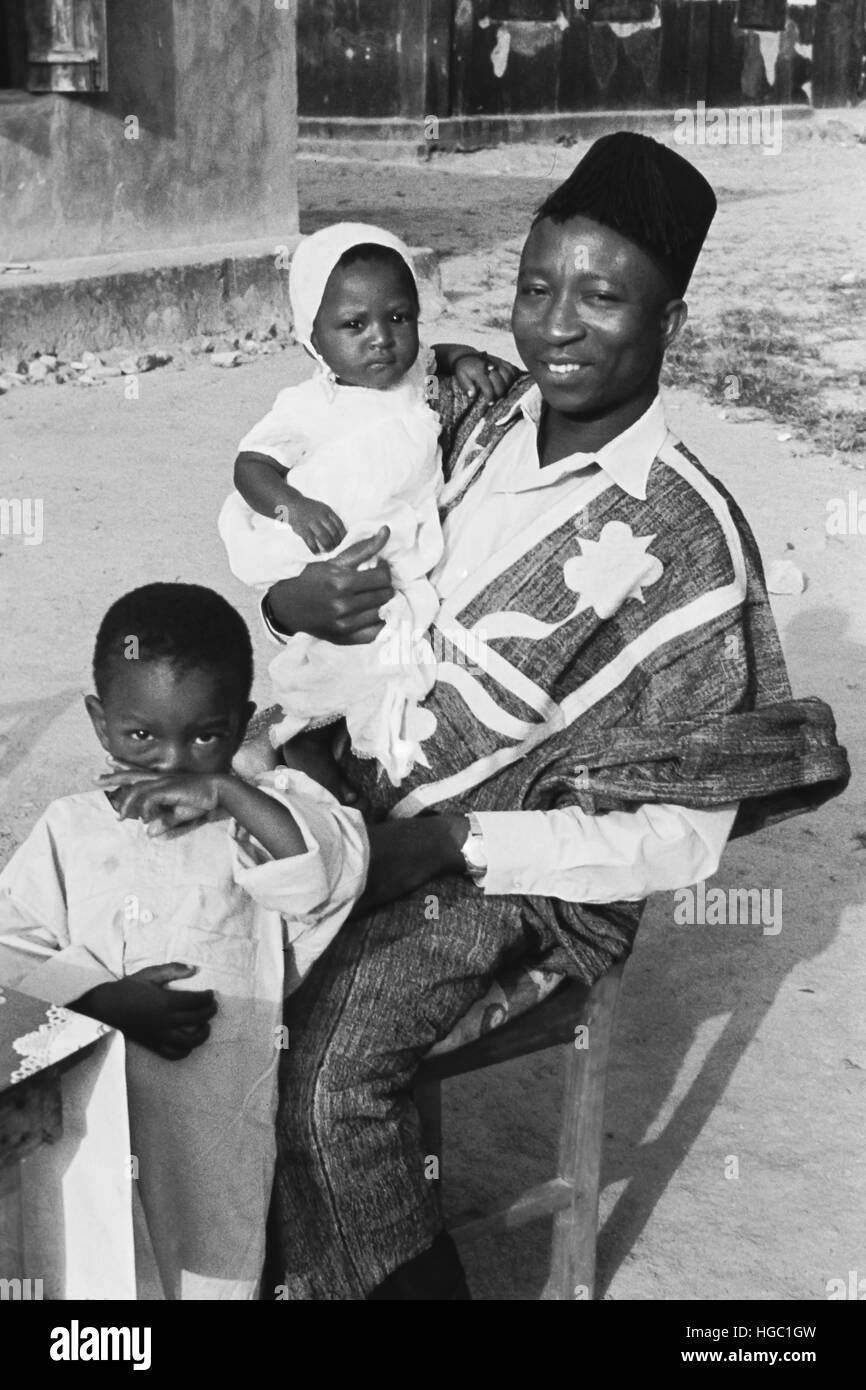 Ein Schneider mit zwei Kindern in Jaiama Nimi Koro, Sierra Leone, 1963. Stockfoto