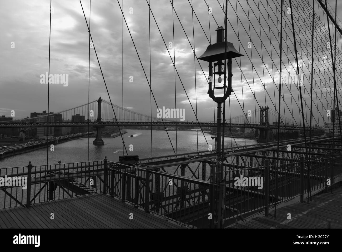 Blick auf die Manhattan Bridge bis zum East River von der Brooklyn-Brücke bei Sonnenaufgang Monochrom, schwarz / weiß Stockfoto