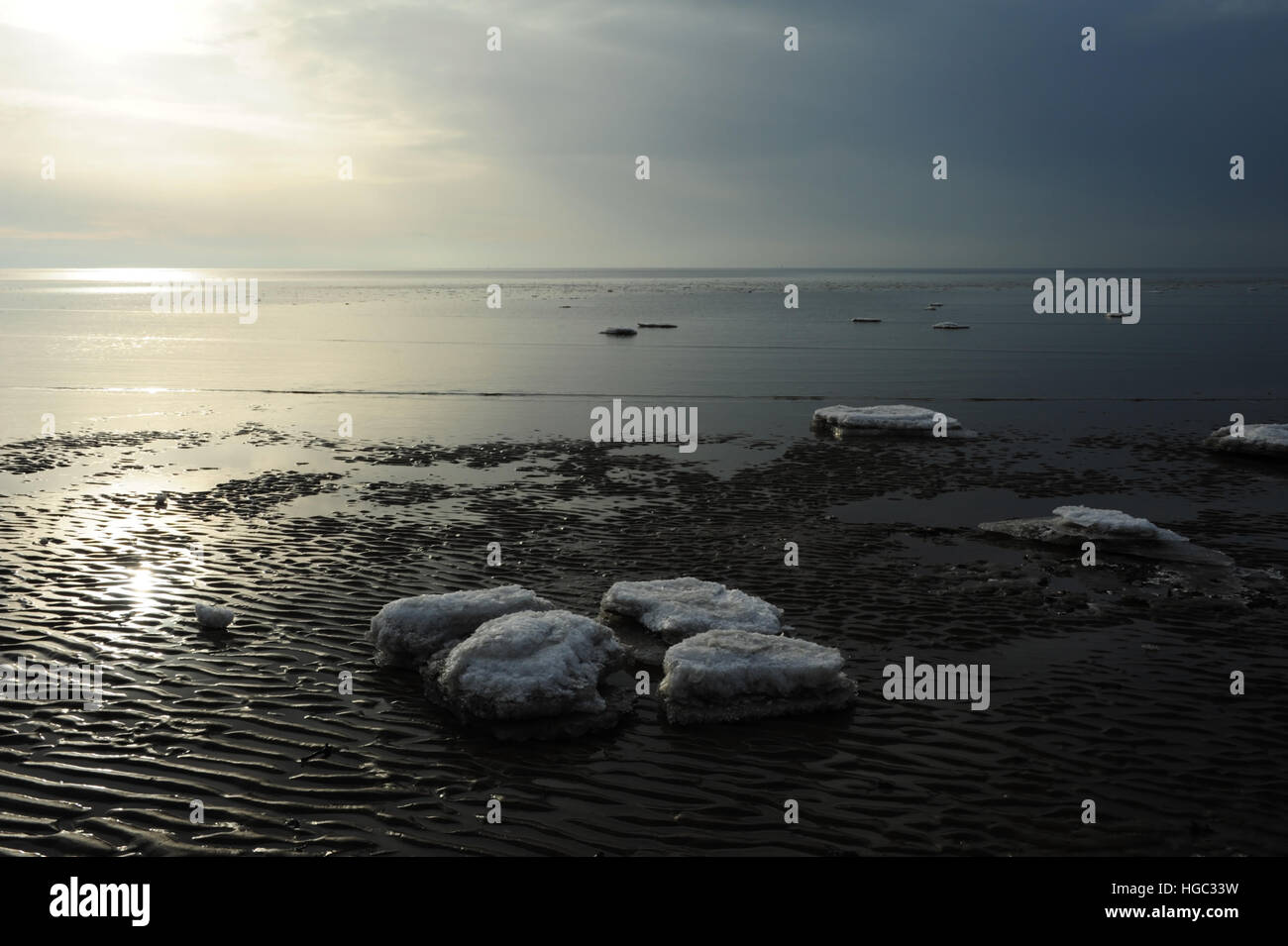 Graue Wolken weiß Sonnenschein Ansicht See Eisblöcke auf Sand Wellen am Rand von ruhigem Meerwasser, Strand östlich von St. Annes, Lancashire Stockfoto