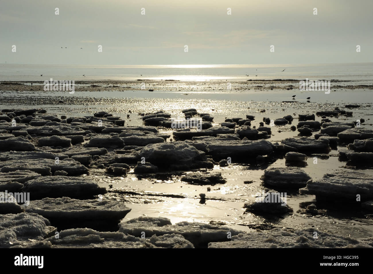 Blauer Himmel trübe Wolken Sonnenschein Blick Meer Eisblöcke auf Sand in Richtung ruhigem Meerwasser, Strand östlich von St. Annes, Lancashire, UK Stockfoto