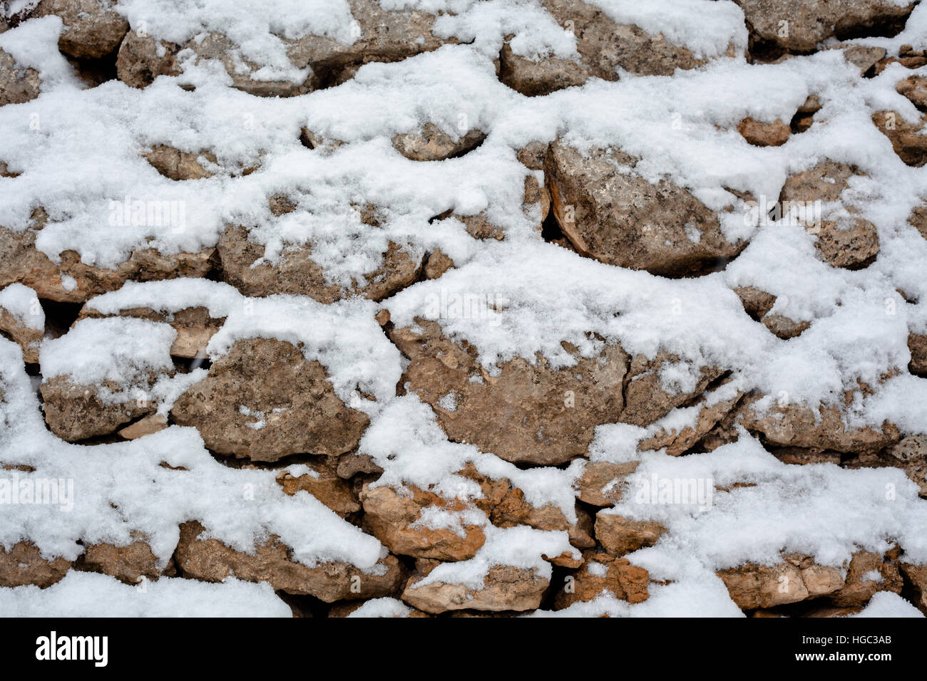 Steinmauer mit weißem Schnee bedeckt Stockfoto