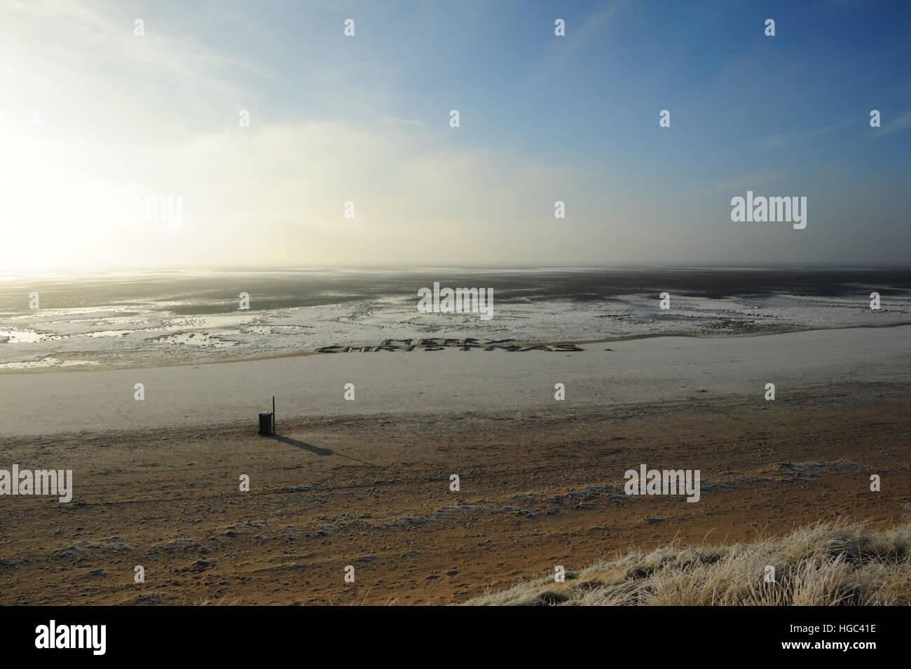 Blauer Himmelsblick vom frostigen Sanddünen über weite Sandstrand mit Meereis und 'Frohe Weihnachten' Inschrift, St Annes, UK Stockfoto