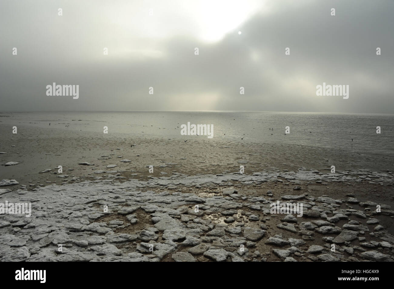 Graue Wolken sehen Land schnell Meer Eisblöcke am Rande des zurückweichenden Meerwasser mit Eisschollen, Strand östlich von St. Annes, Lancashire Stockfoto