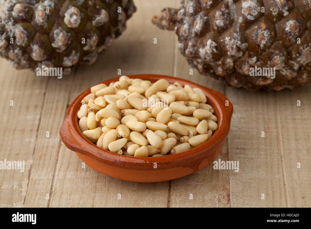 Schale mit Pinienkernen mit frisch Pinoli, Tannenzapfen im Hintergrund Stockfoto