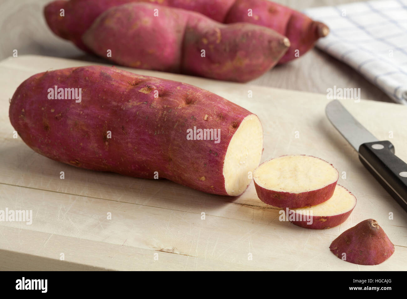 Lila Süßkartoffeln mit Scheiben auf ein Schneidebrett Stockfoto