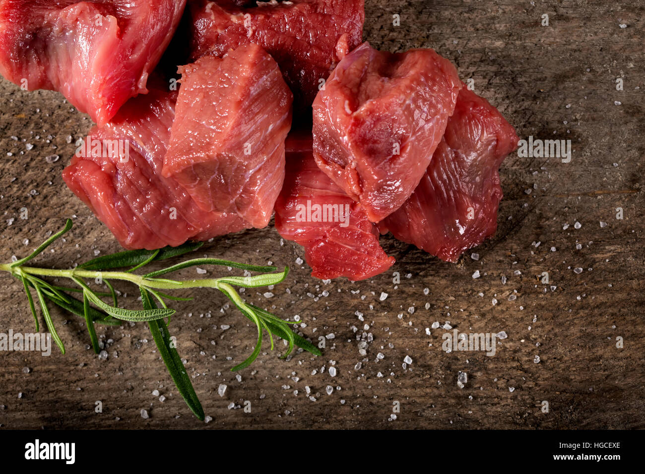 Rohes Rindfleisch mit Rosmarin und Salz auf alten rustikalen hölzernen Hintergrund Stockfoto