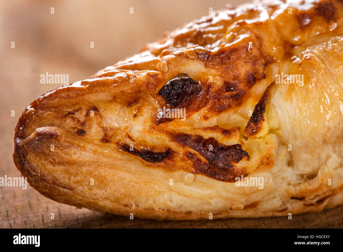 Nahaufnahme von einem Stück Käse Patty verschmiert mit Honig und Sesam Samen auf hölzernen Hintergrund Stockfoto