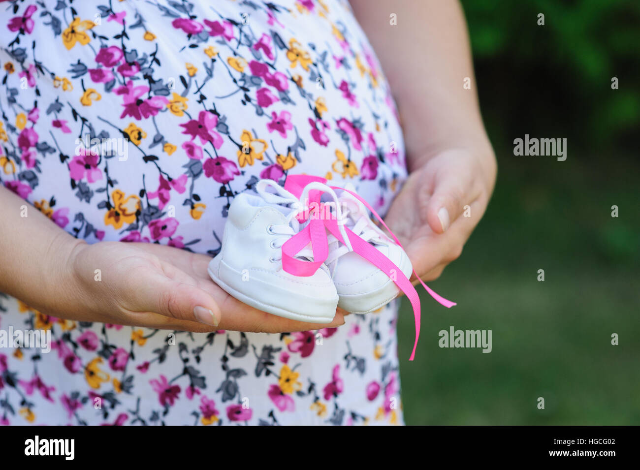 Schwangere junge Mutter hält weiße Schuhe Kind Stockfoto