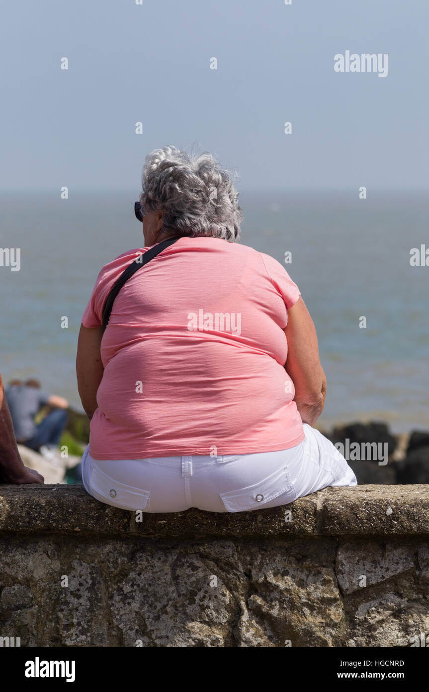 Fette Frau auf einer Mauer sitzend Stockfotografie - Alamy