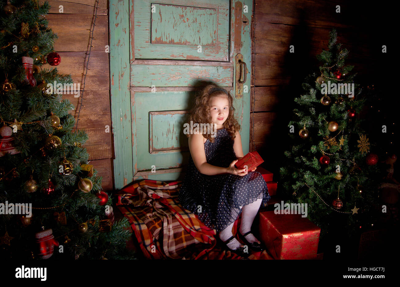 Glückliches kleine Mädchen schmücken Weihnachtsbaum im schönen Wohnzimmer mit traditionellen Kamin. Stockfoto