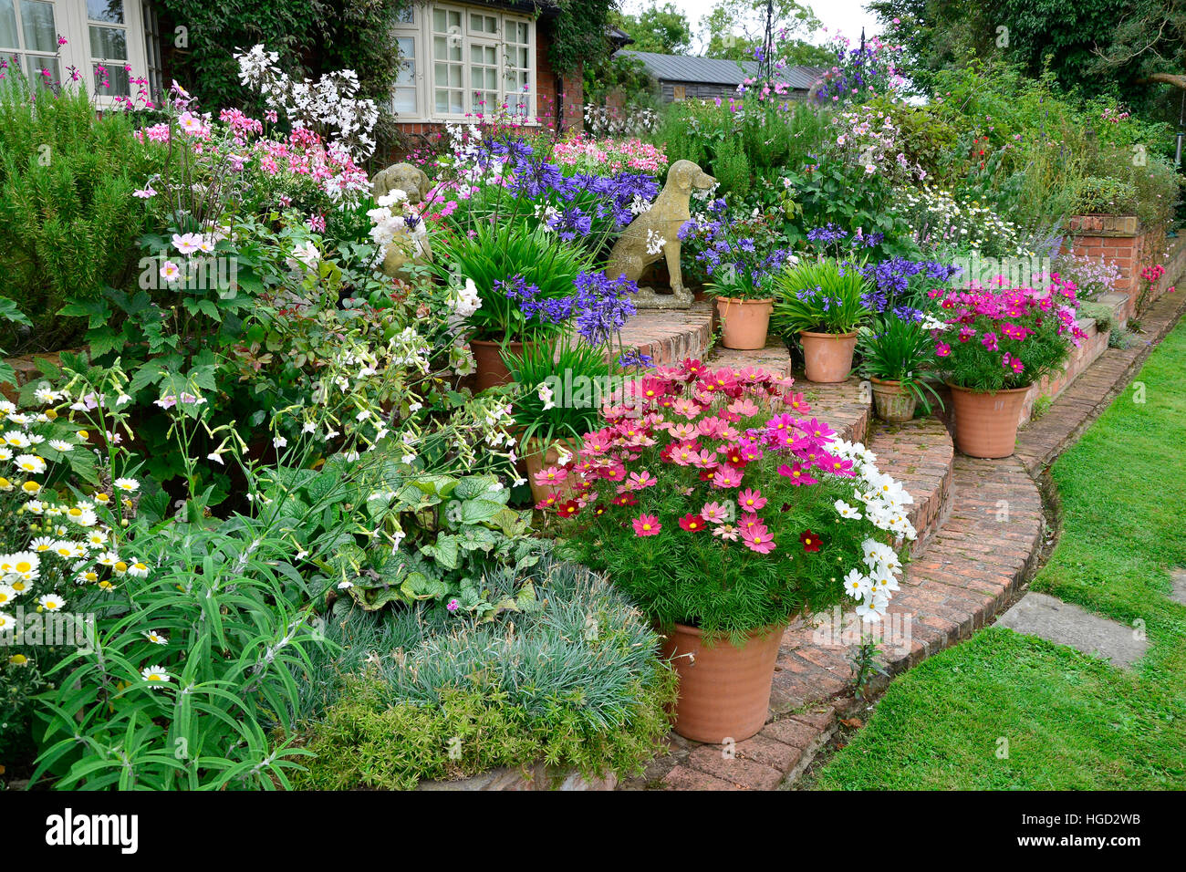 Bunte Garten-Terrasse mit gemischten Beeten und bepflanzten Container machen eine sehr attraktive vor einem Landhaus anzeigen Stockfoto