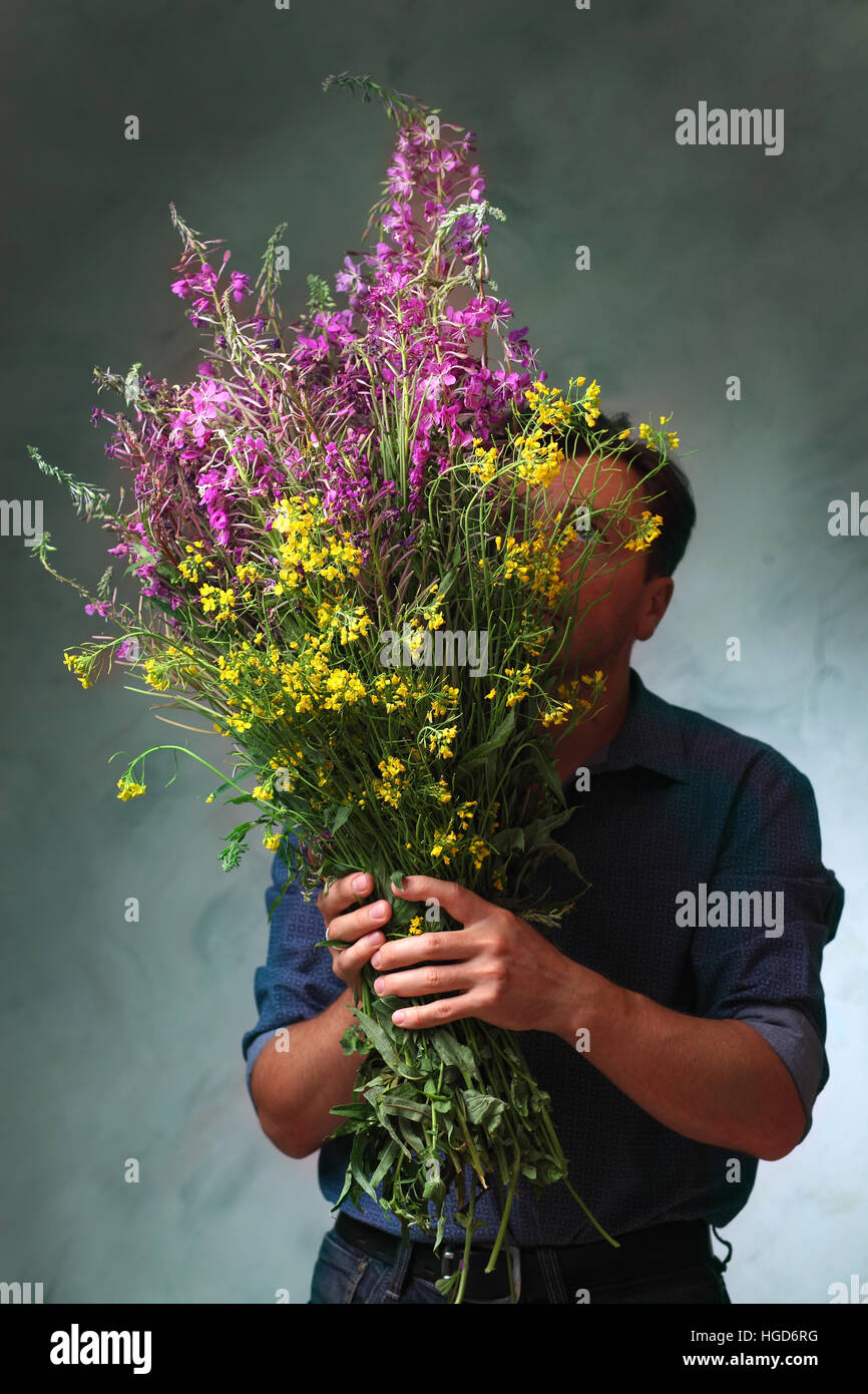 Mann hält einen großen Strauß von Wildblumen, ein Mann kam auf ein Date mit Blumen, man wartet auf seine Liebe Stockfoto