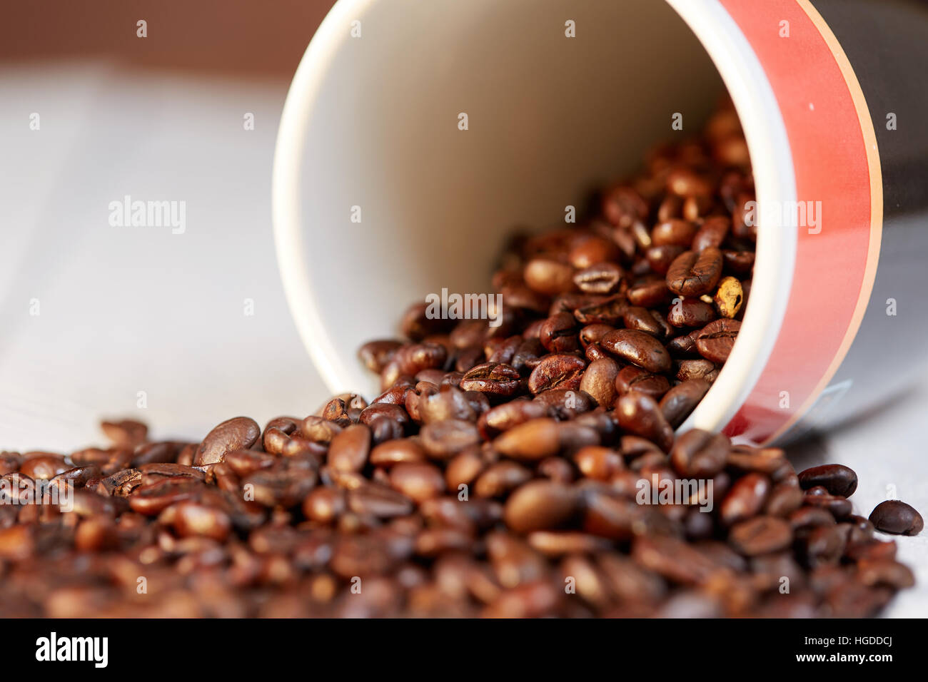 Kaffee Bohnen Makro in Cup am weißen Tisch verstreut Stockfoto