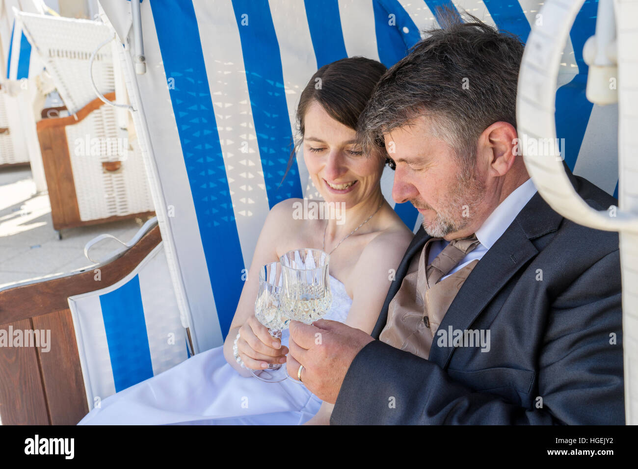 Ein Brautpaar sitzt im Strandkorb und trinkt Champagner Stockfoto