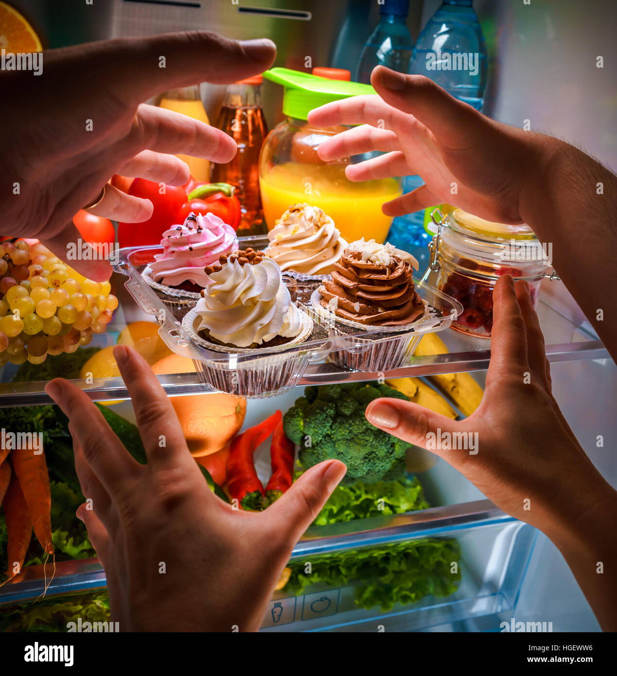 Menschliche Hände für süße Kuchen nachts in den offenen Kühlschrank Stockfoto