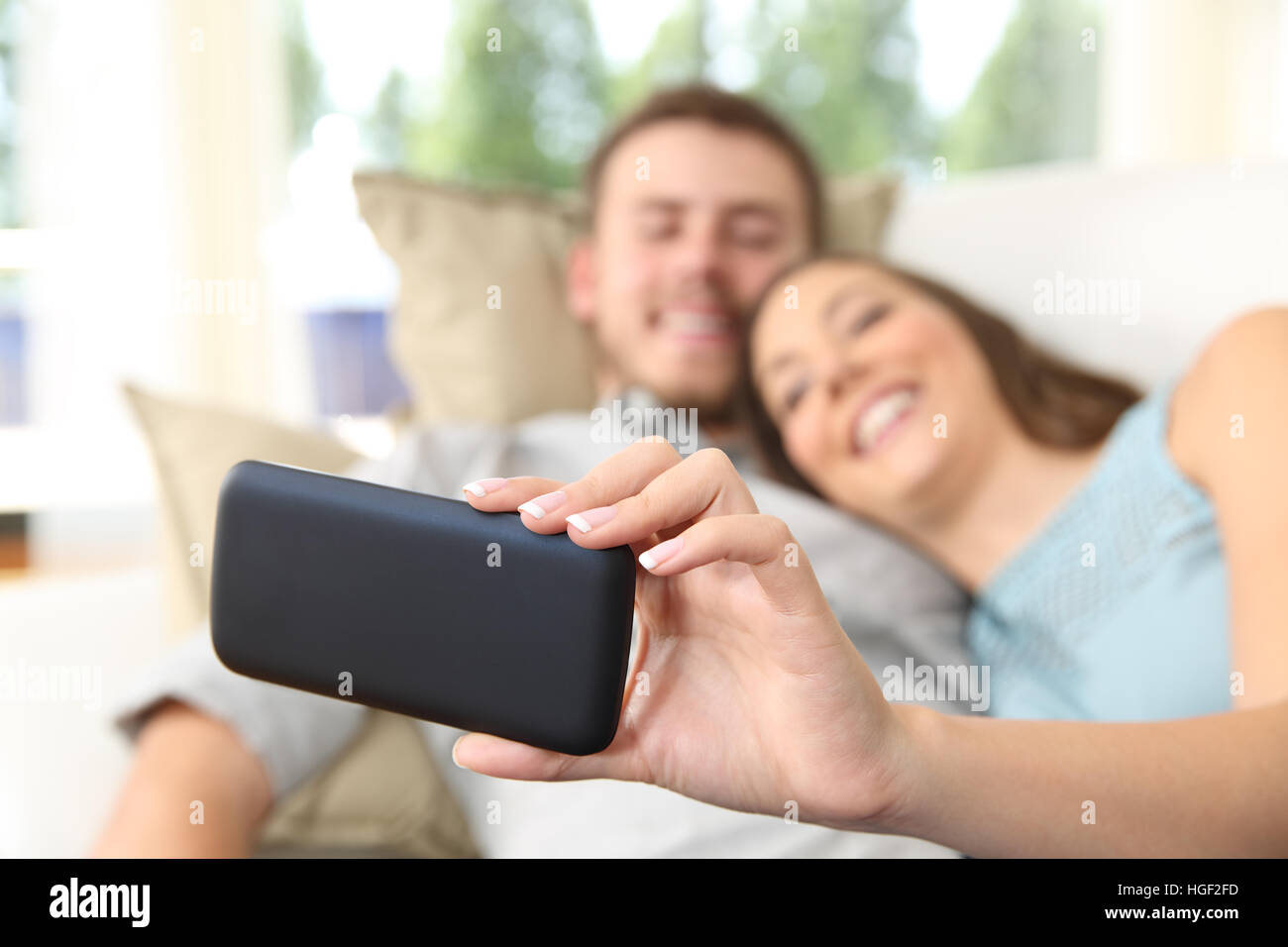 Nahaufnahme von ein paar beobachten Medien in einem Handy oder Selfies liegen in einer Couch zu Hause zu Stockfoto