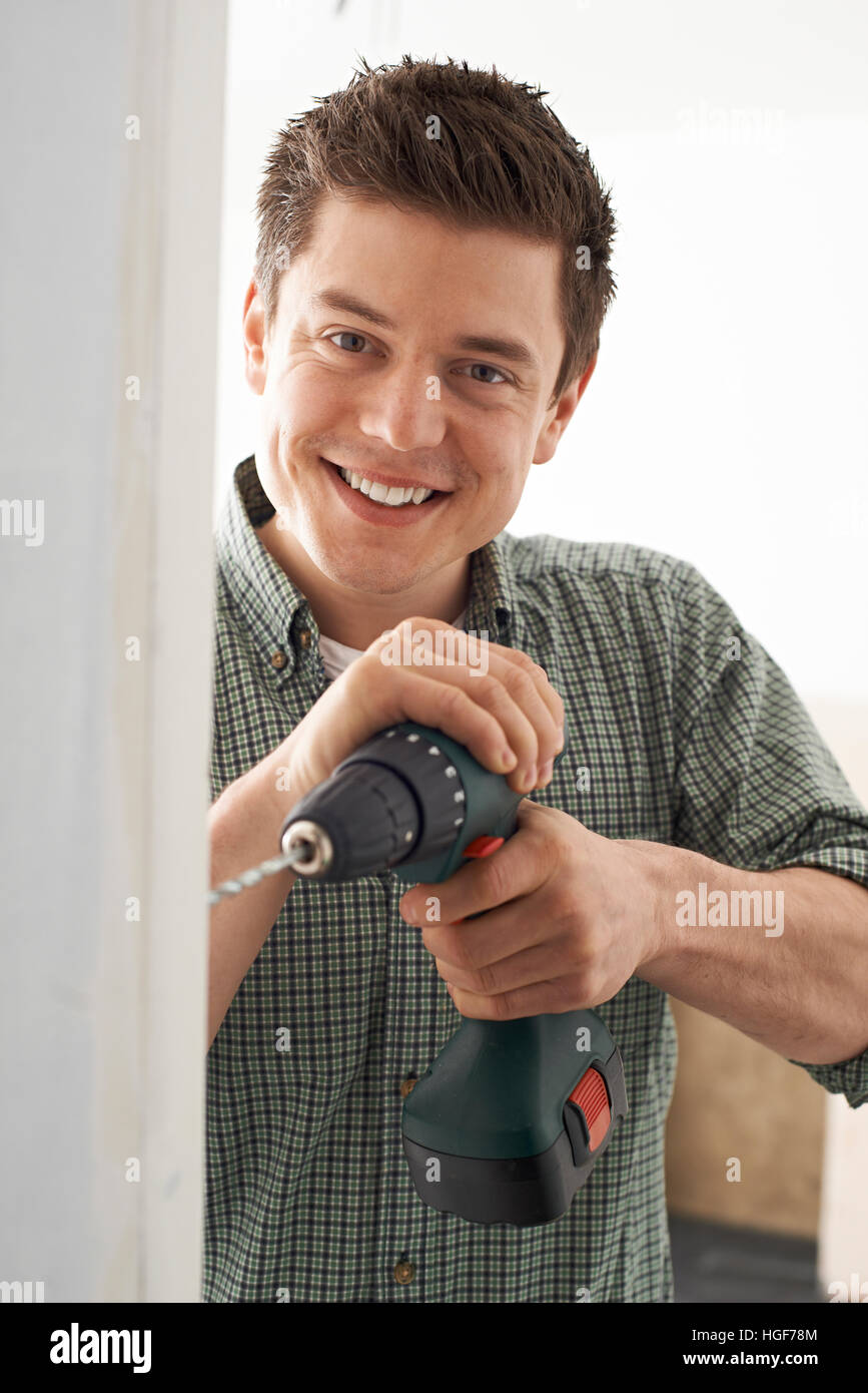 Junger Mann mit elektrischen Bohrer im Haus Renovierung Stockfoto