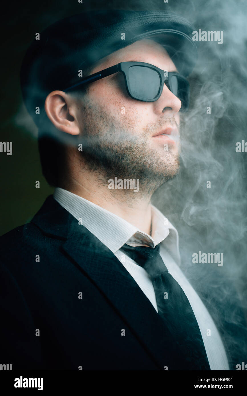 Männchen tragen Sonnenbrillen und eine Lederkappe im Rauch Stockfoto