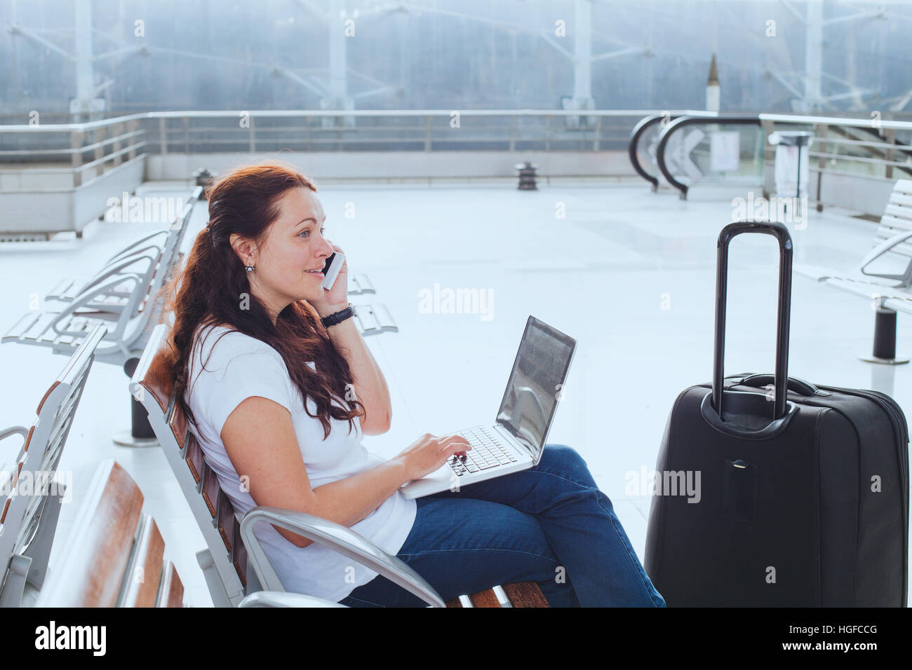 Frau im Flughafen im Gespräch per Telefon und e-Mails am Laptop, Geschäftsreisen, mobile WiFi-Verbindung Stockfoto