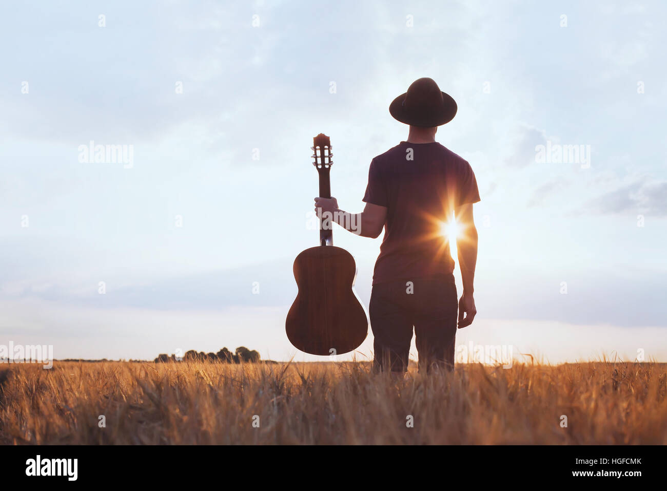 Musik Festival Hintergrund, Silhouette der Musiker Künstler mit akustischer Gitarre bei Sonnenuntergang Feld Stockfoto