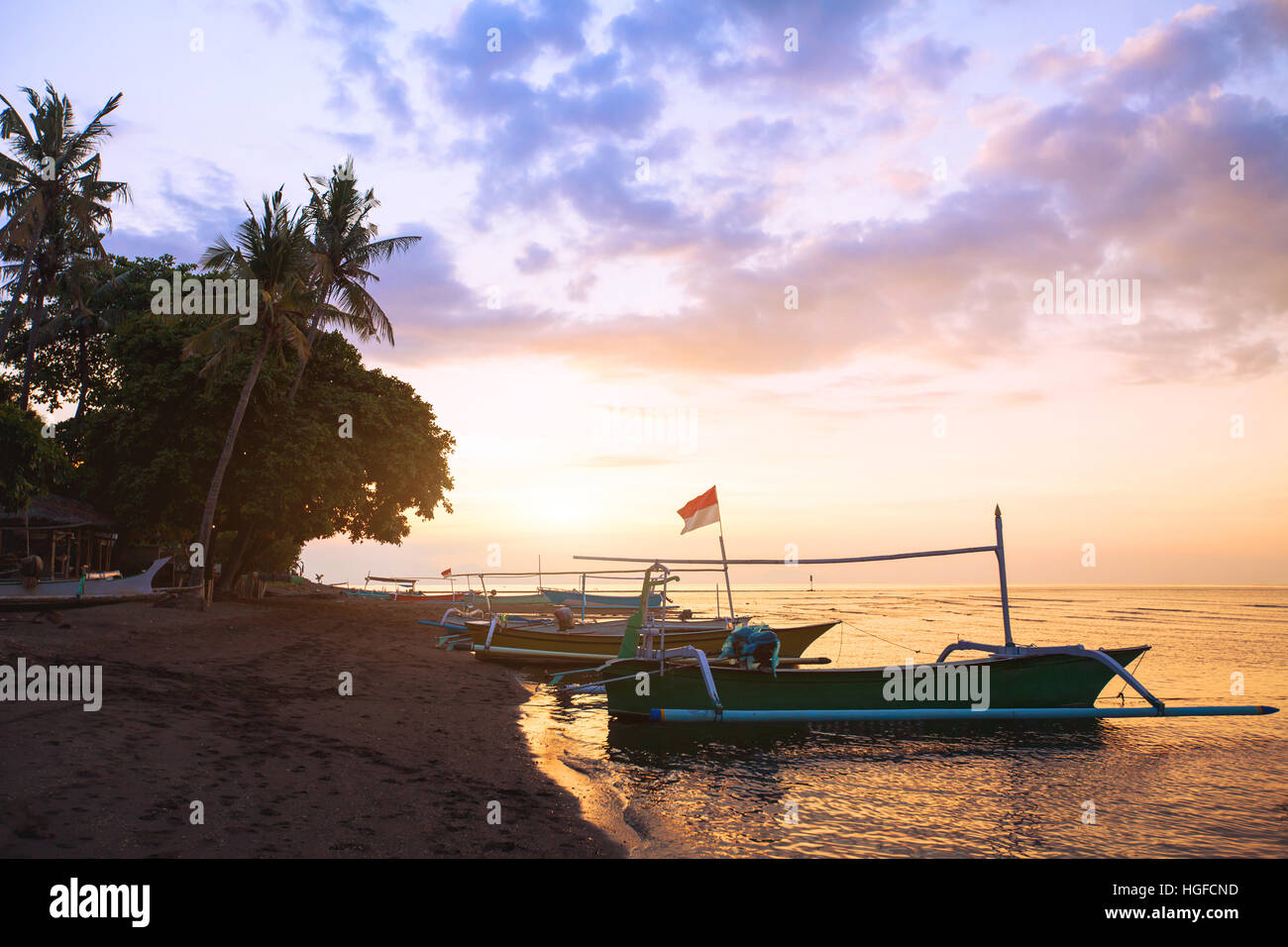 Schöner Strand auf Bali bei Sonnenuntergang, exotische Landschaft mit Boote und Palmen. Stockfoto