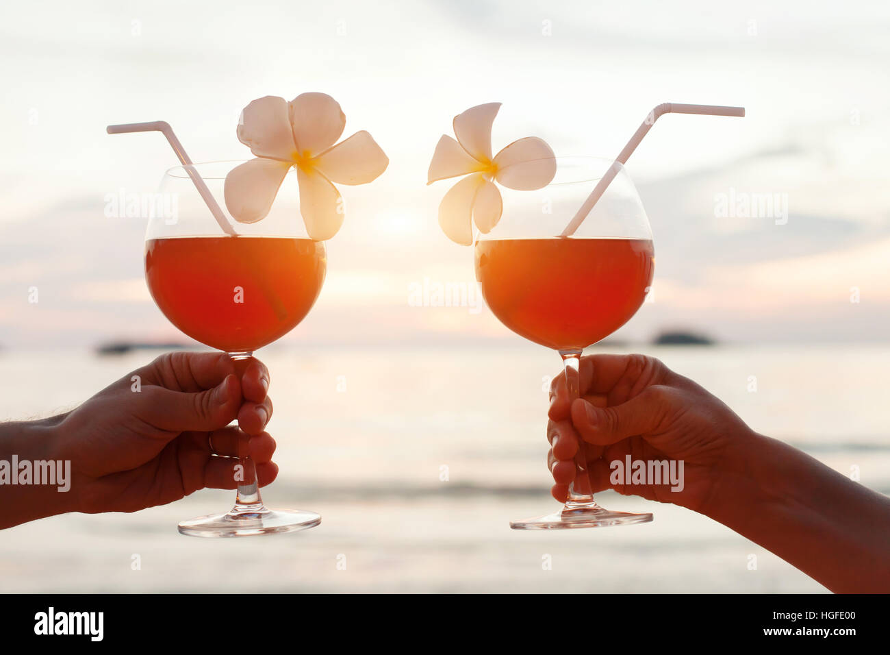 Flitterwochen-Feier am Strand, paar jubeln mit tropischen Cocktails bei Sonnenuntergang Stockfoto
