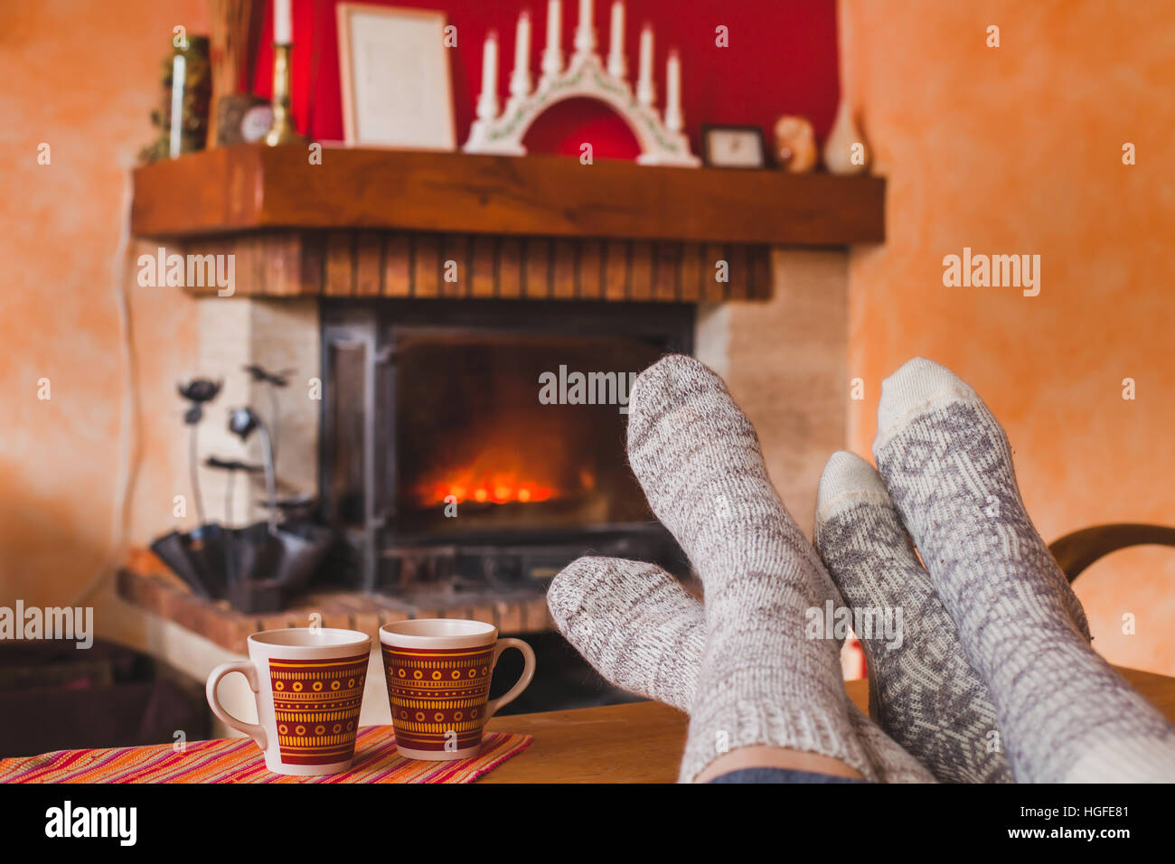 Wochenend-gemütlichen Familienabend zu Hause in der Nähe von Kamin im Winter, Füße des Paares in Socken und zwei Tassen Tee, Stockfoto