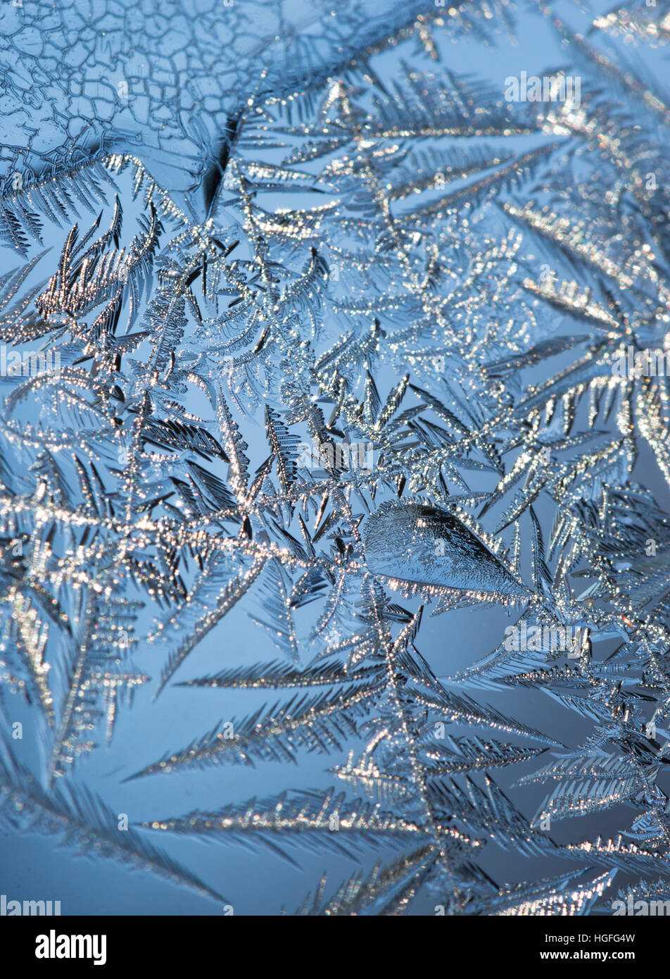 Nahaufnahme der Eiskristalle bilden komplizierte grünen Muster auf ein Fenster mit blauen Himmel im Hintergrund. Geringe Schärfentiefe. Stockfoto