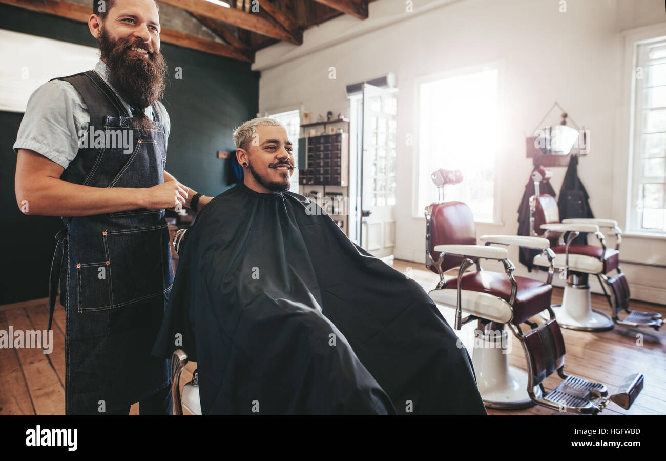 Friseur mit Kunden im Salon sitzen und Lächeln auf den Lippen. Hipster-Mann immer Haarschnitt beim Friseur. Stockfoto