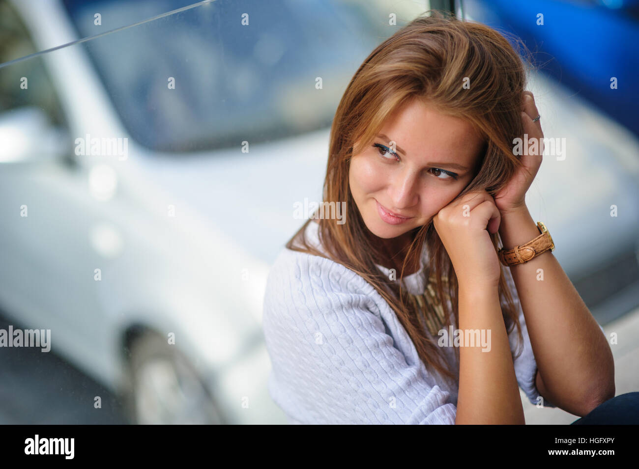 junge schöne Frau posiert vor Hintergrund des Autos Stockfoto