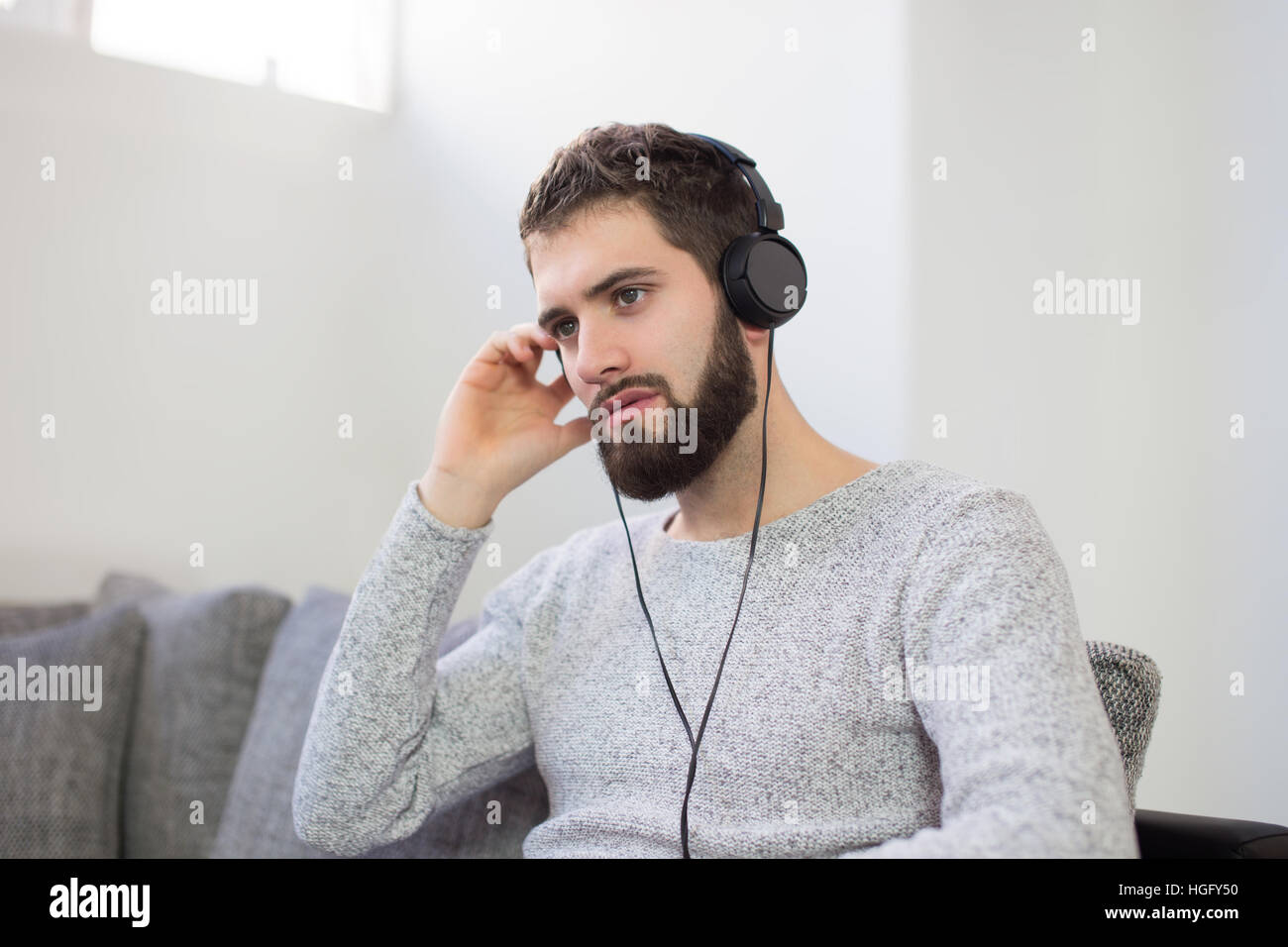 Junger Mann hören Entspannungsmusik indoor, auf sofa Stockfoto